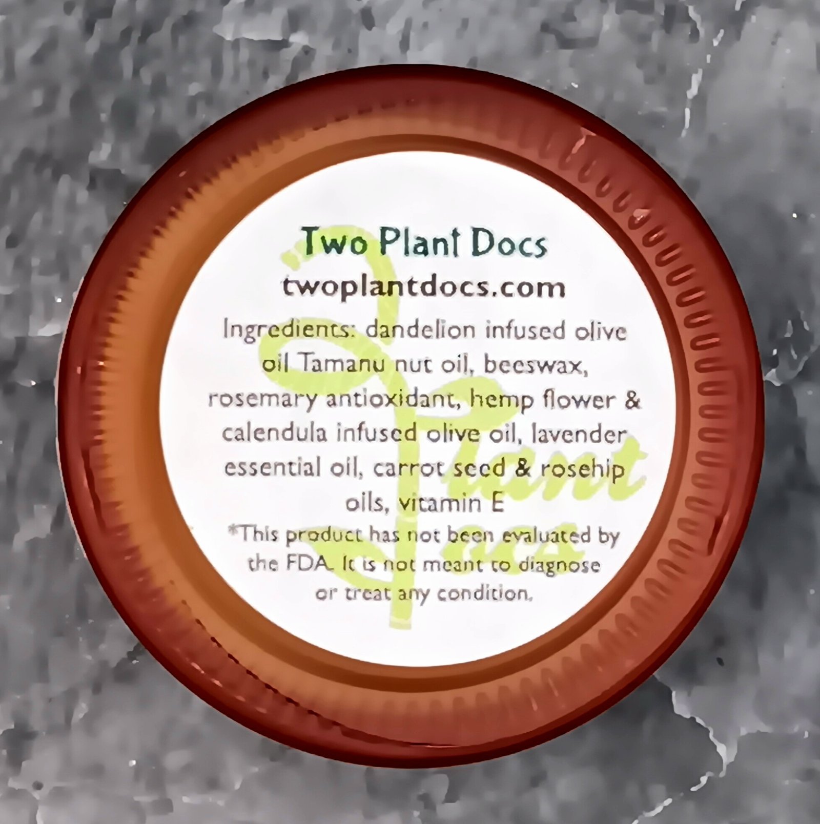 Bottom of a pink jar with ingredients listed: Ingredients: dandelion infused olive oil Tamanu nut oil, beeswax, rosemary antioxidant, hemp flower & calendula infused olive oil, lavender essential oil, carrot seed & rosehip oils, vitamin E