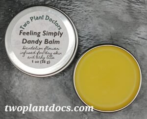An open tin of bright yellow balm and a closed tin